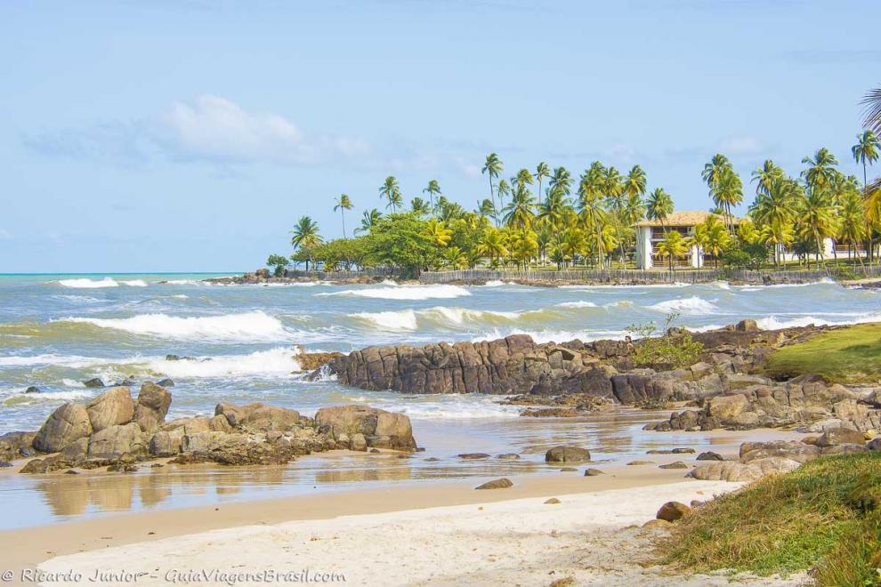 Imagem das pedras e das onda na praia.